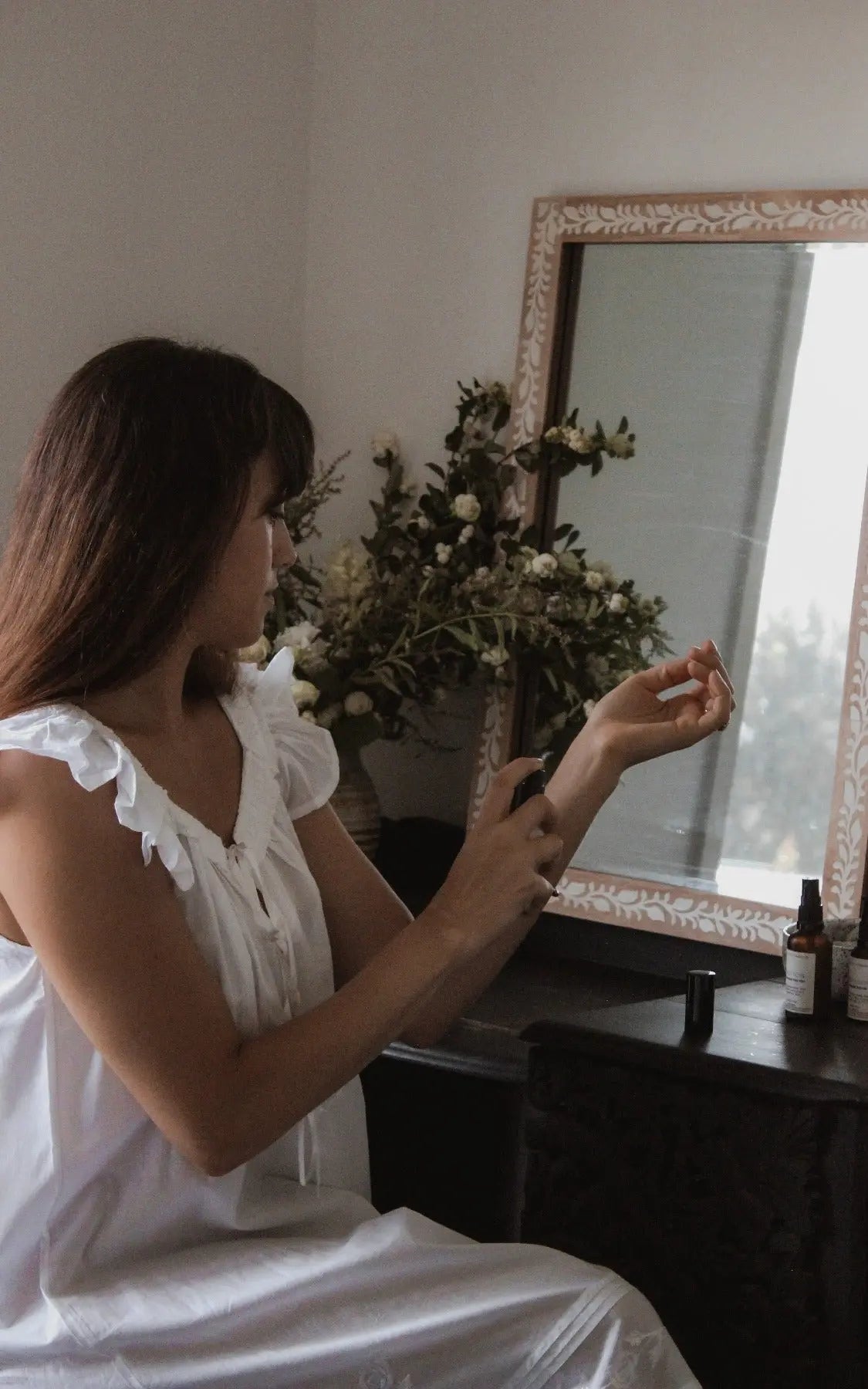 woman misting perfume at dressing table